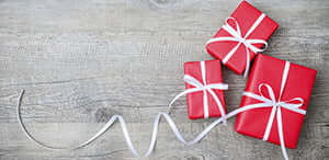 Three beautifully wrapped red gift boxes with white ribbons on a wooden surface. Perfect for any occasion!