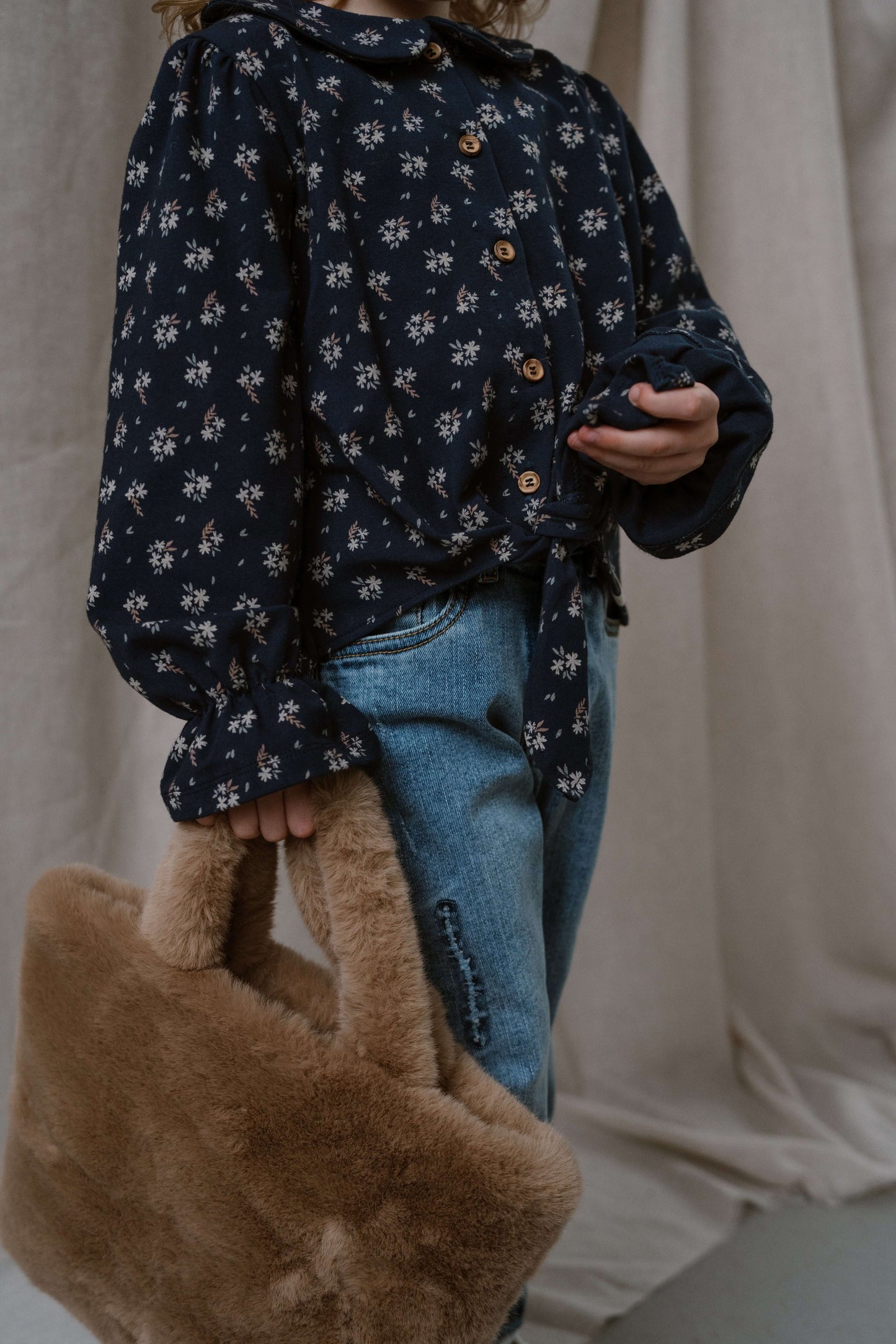 Charming Navy Natural Faye blouse in dark blue floral design, paired with denim and a stylish fur handbag.