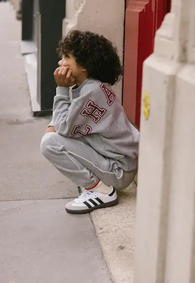 Kind in grijze Jordan sweatpants en Adidas sneakers, ontspannen in de stad, perfect voor stijl en comfort.