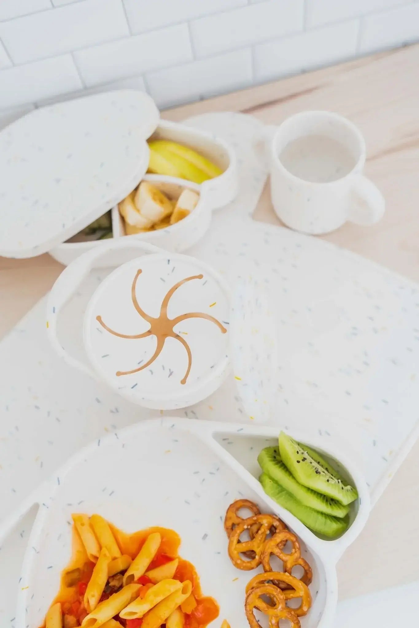 Cotton Cloud Milo confetti lunchbox with snacks, fruits, and drink cup on a wooden table. Perfect for kids' meals!