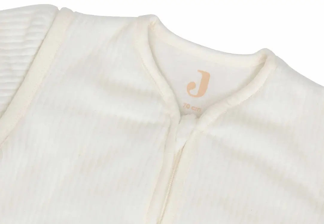 Close-up of Jollein ivory sleep sack with ribbed texture, featuring a comfortable zipper and size tag.