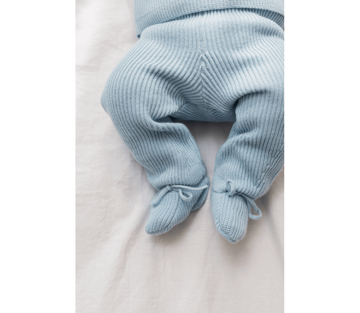 Soft blue knitted newborn pants with elastic waistband and tied cuffs, made from 100% organic cotton.