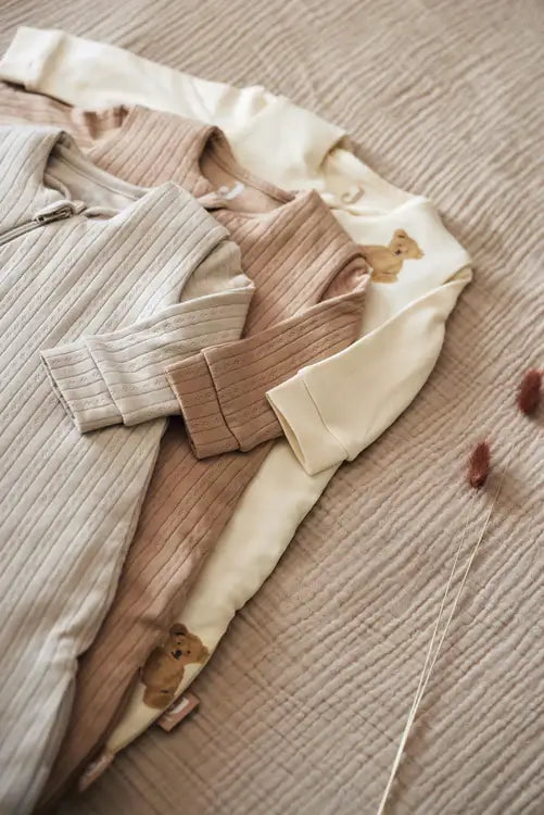 Three cozy Jollein newborn sleep bags in soft tones, featuring adorable bear prints on a textured background.