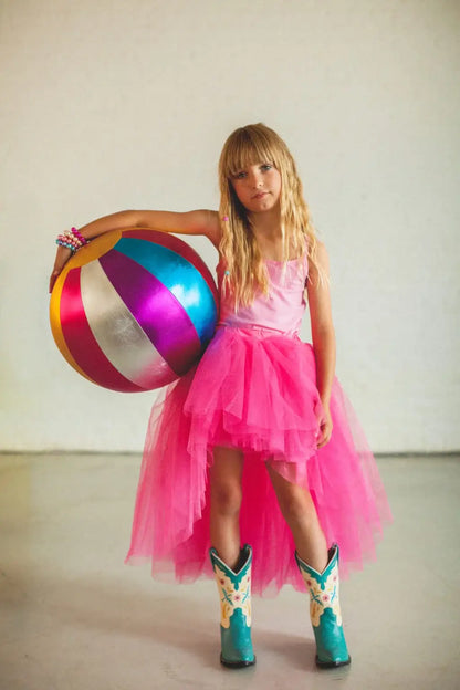 Young girl in a pink tutu and cowboy boots, holding a colorful metallic beach ball for indoor play.