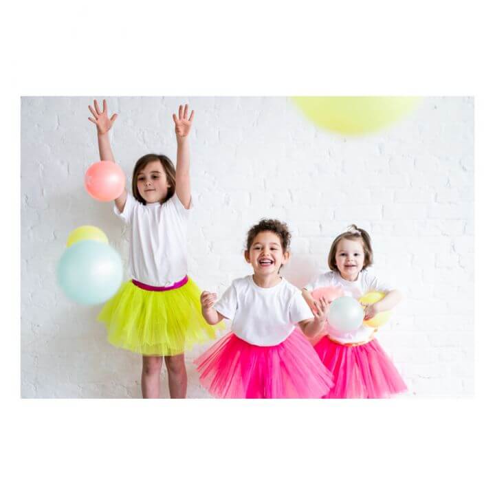 Kids in colorful tutus playing joyfully with balloons against a bright background, perfect for festive celebrations.